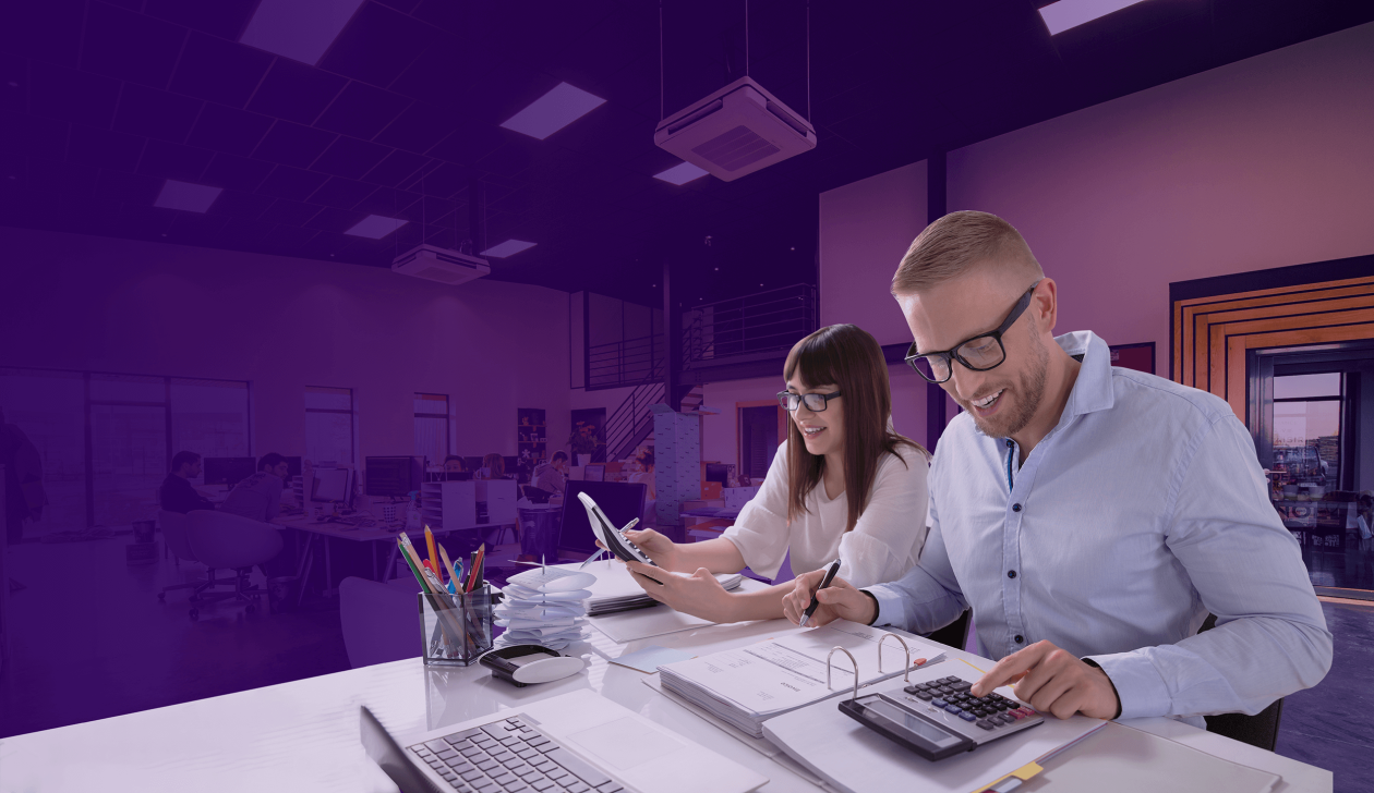 Back-office team using software to manage job scheduling and invoicing with laptop, paperwork and calculator in a modern office — FieldInsight.